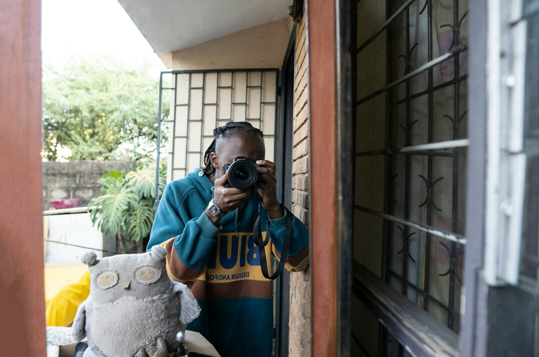 Photographer documenting a resident's story with camera and notebook